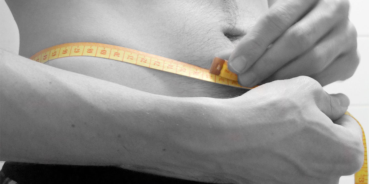 close up image of a man measuring his torso with a measuring tape